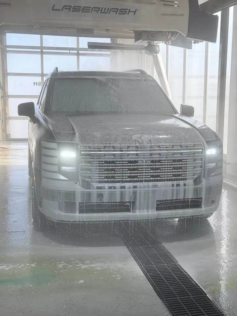 A truck covered in foam in the touchless automatic bay, under the LaserWash gantry