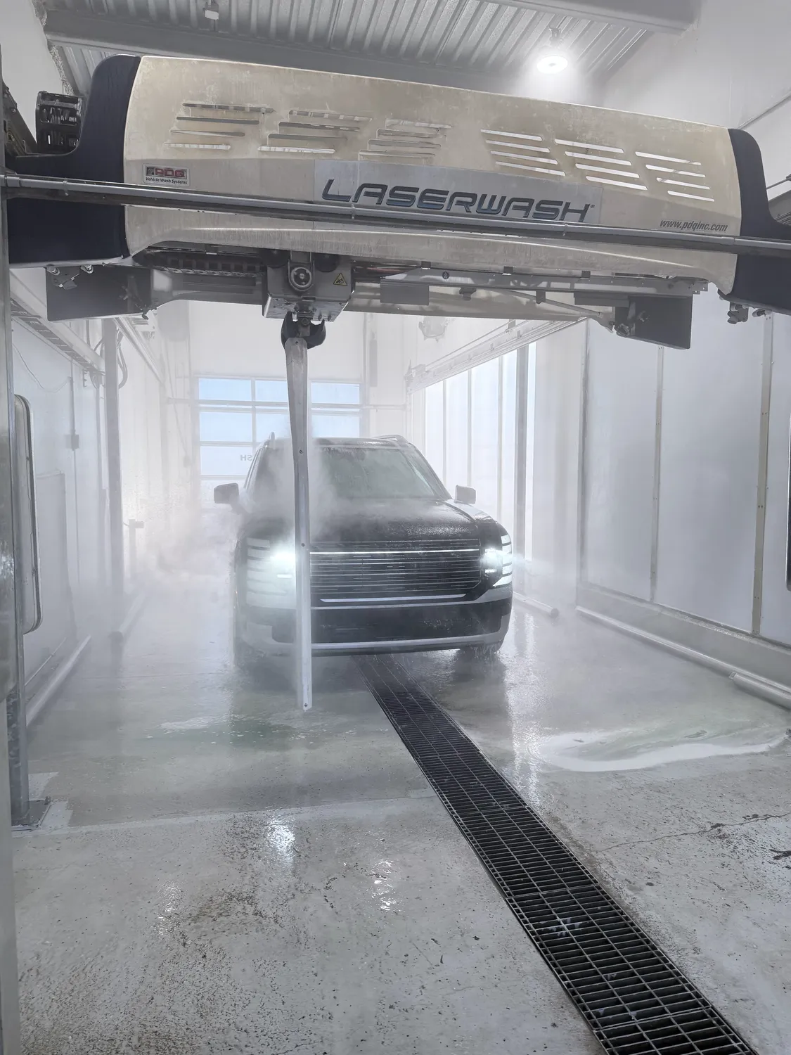 A vehicle in the touchless automatic bay, the LaserWash gantry overhead and its arm spraying high-pressure water